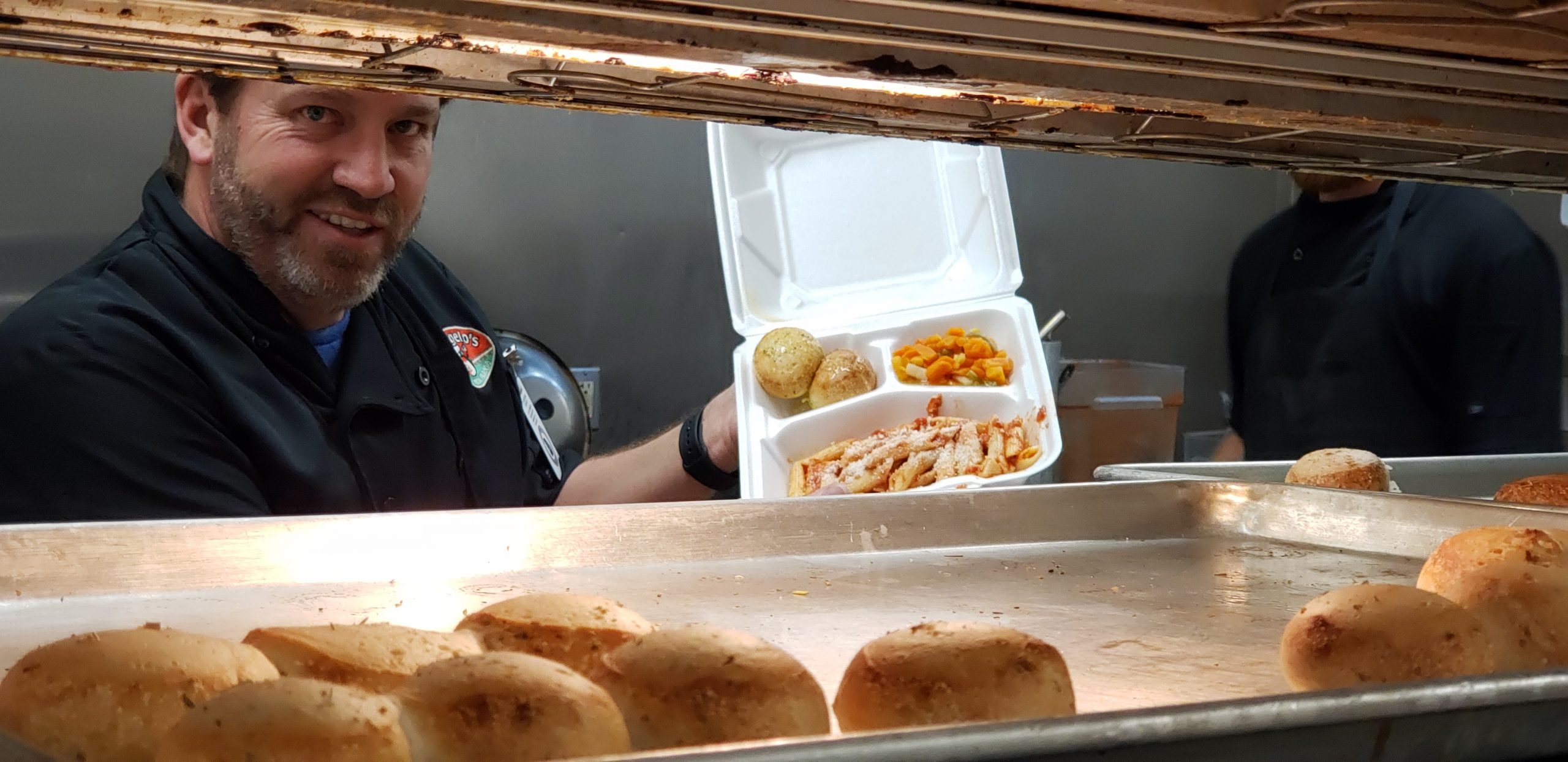 Volunteer making to-go meals with potatoes, mixed vegetables, and pasta
