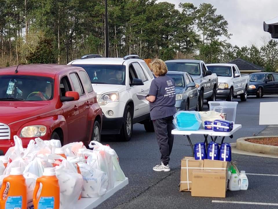 Patrons in drive-thru line receiving household and personal items, such as laundry detergent and feminine hygiene products from Red Door Food Pantry in Cartersville, Georgia